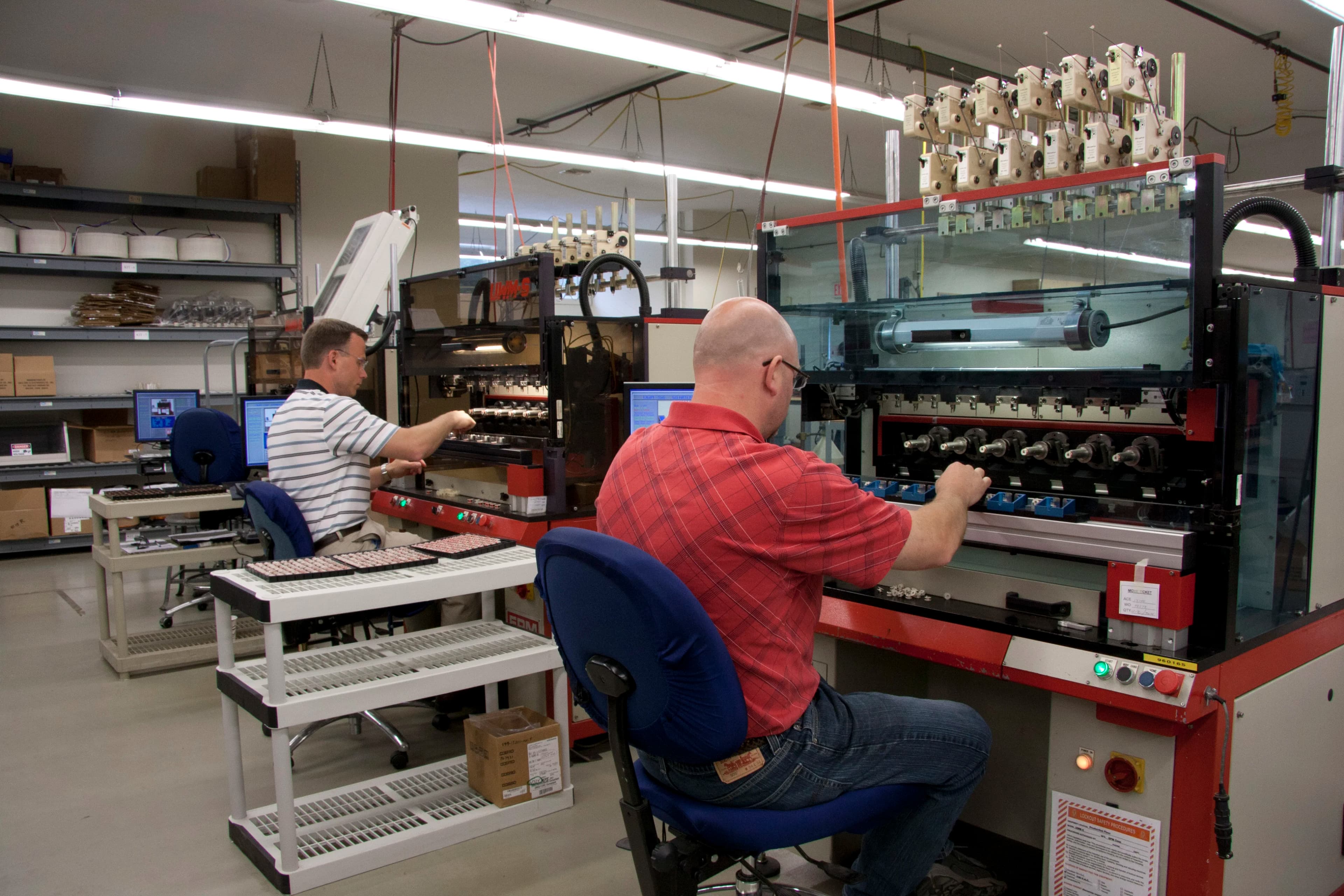 Two workers manufacturing electromagnetic coils on automated coil winding machines